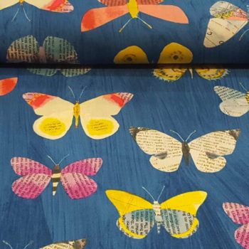 Primer plano de tela de algodón azul con estampado de mariposas multicolores en tonos rosa, amarillo y blanco para acolchado y labores