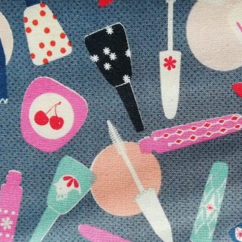 Tela infantil maquillaje** de algodón 100% con estampado de brochas, espejos y cosméticos sobre fondo claro de 1,10m de ancho