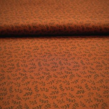 Primer plano de tela de algodón color óxido teja con estampado de ramilletes de flores y hojas pequeñas en tonos crema para acolchado